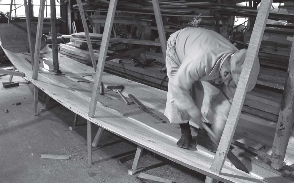photo of a man building a wooden ship