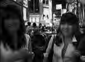 two women smiling on a crowded street