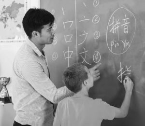 photo of a teacher and a young student writing on a blackboard