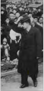 photo of a man in a suit walking by a crowd of people