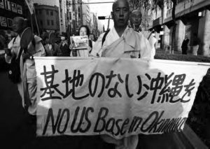 people holding a sign for no us base in okinawa