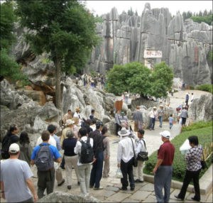 photograph of a large group of people walking up a path to a shrine