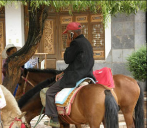photo of a man on a horse talking on a flip phone