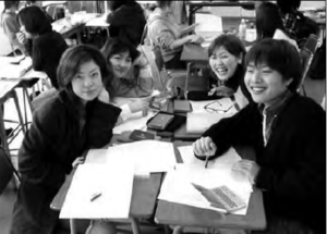 photo of a group of students sitting at their desks smiling for the photo