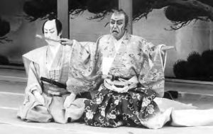 two kabuki figures with exaggerated faces kneel