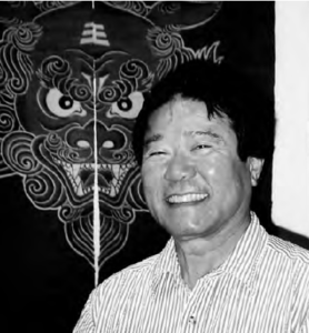 a young man smiles in front of an illustration of a lion face