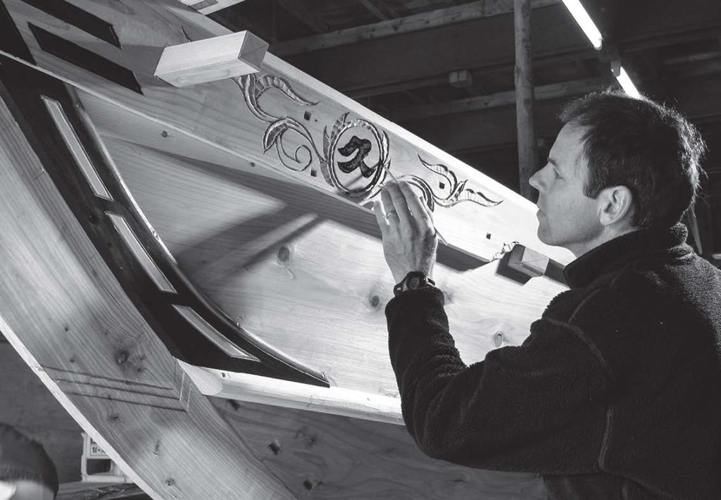 photo of a man painting on a wooden ship