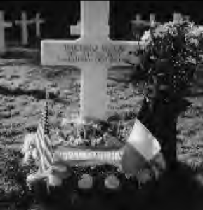 Photograph of Hachiro Mukai's grave with a French and United States flag, flowers, and a large inscribed cross.