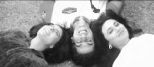 three people lay on the ground with their heads together, laughing