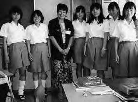 a group of school girls and an older woman pose smiling for a photo