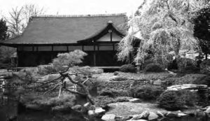 a house with a roof that comes up in points at each end. It sits behind a garden landscape