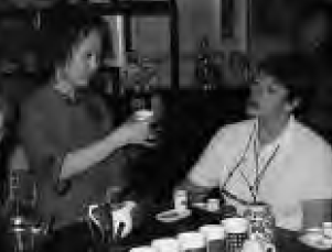 a woman holds up her teacup for another woman to see