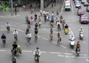 a photo of many people biking and riding mopeds on a street