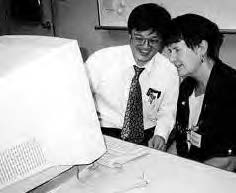 two smiling people sit and look at a computer screen
