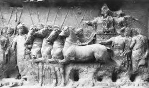 carved relief of man on chariot with many horses and attendees