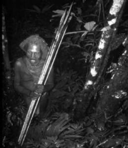 A man walking in the forest with bow and arrows in his hand.