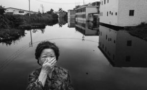 Image of a old woman covering her mouth with her hand standing front wastewater