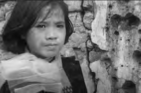 Ngọc Hà gazing at her ruined home and neighborhood.