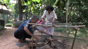 A Cambodian wife and husband working together smoking fish.