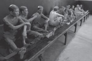 photo of many mannequins with their legs chained to a platform. there is no room in between people