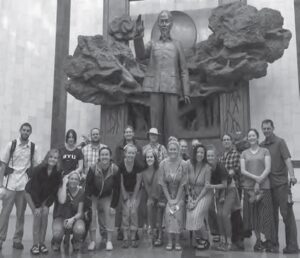 photo of a group of people in front of a statue of a man with his hand up and outstretched