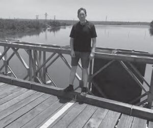 photo of a man standing on a bridge with water in the background