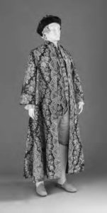 a mannequin stands garbed in a floral patterned robe and velvet cap.