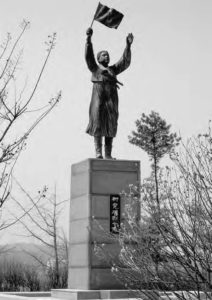 statue of a woman with her arms up, holding a flag