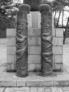 a photograph of two small pillars, decorated with images of dragons facing each other. 