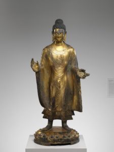 bronze figure that has its hands up and palms out