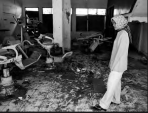 Image shows a woman standing in the destroyed room