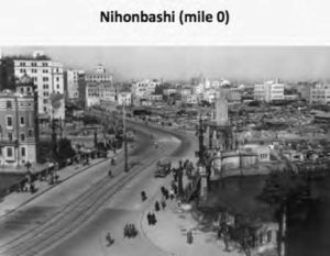 an old photograph of a road with buildings, a few of which are a few stories tall