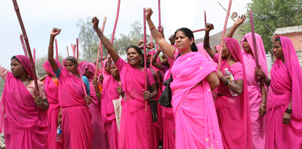 Photo of women dressing in shades of bright pink and holding up their right hand