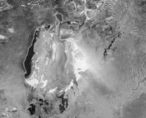 A pale beige plume of dust blows from the sediments of the South Aral Sea toward the southeast, along the Kazakhstan–Uzbekistan border. 