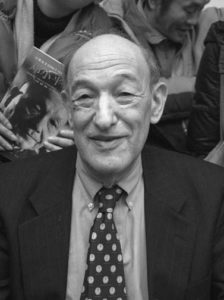 Photograph of a smiling elderly white man wearing a Western business suit and a polkadot tie. 
