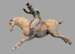 A Tang Dynasty ceramic sculpture depicting a female polo player from northern China. The sculpture showcases a woman on horseback, dressed in traditional attire, engaged in a dynamic polo game, reflecting the cultural significance of equestrian sports during the Tang Dynasty.