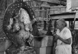 an old woman praying to a statue of ganesha