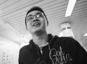 photograph of a young man wearing glasses and a hoodie smiling