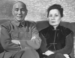 a portrait of a man and woman. The man sits, smiling and arms crossed at the photographer, while the woman looks slightly away