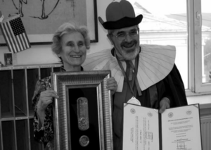 The picture shows a man and a woman holding a certificate of honor