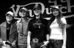 Image shows four people standing front of the slogan of Von Dutch
