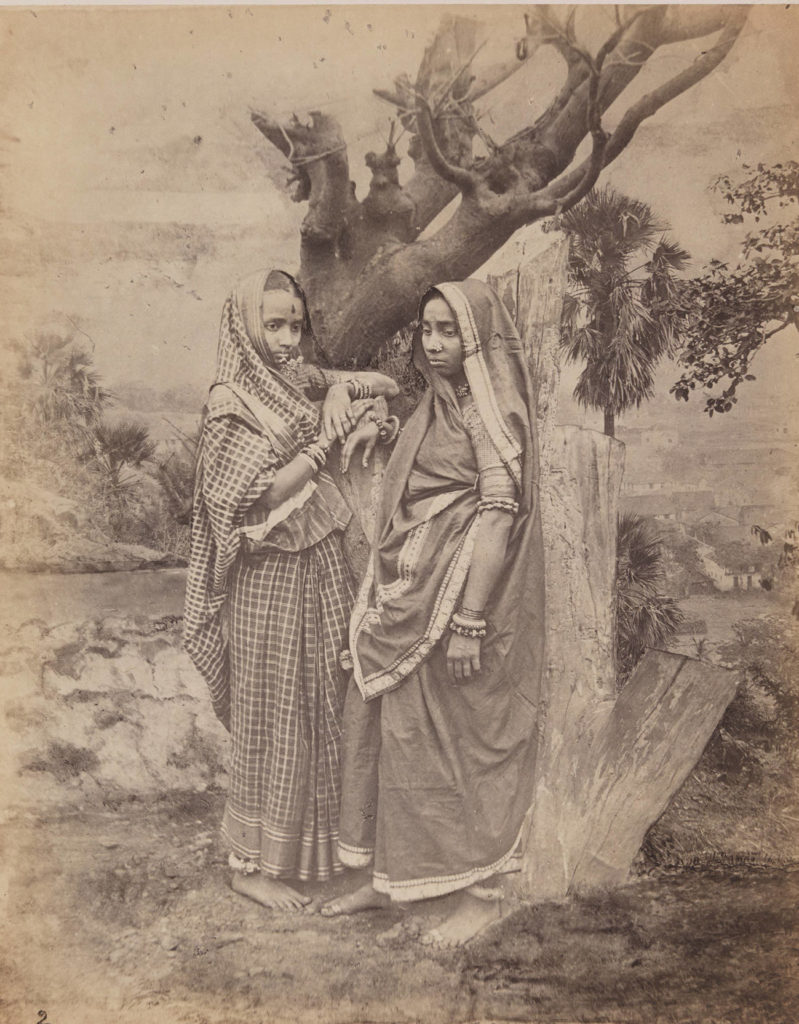 Photograph of two India women under a dead tree with sad face