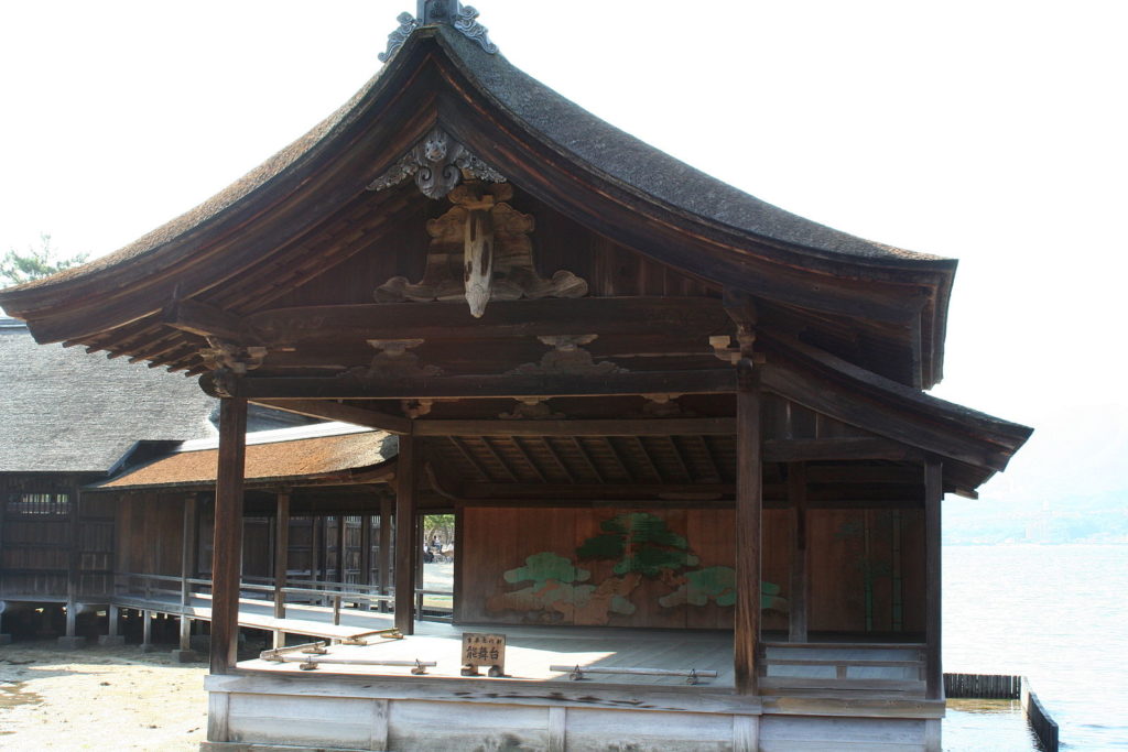 World’s oldest existing Noh stage at Itsukushima Shrine, Miyajima Island, Hiroshima Prefecture, Japan. Noh Stage located at Itsukushima Shrine in Hiroshima nationally designated as an Important Cultural Property. The current stage was built in 1680 (Enpō 8) by the feudal lord of Hiroshima, Tsunanaga Asano (1659-1708). One special characteristic of the stage is that it is built on the beach, and when the tide is full it appears to be floating in the ocean. To enhance the sound of steps of the stage, large pots are typically placed under it, but this is not possible on the Itsukushima Shrine as it is built on the ocean. In place of the pots, other techniques are employed such as widening the space between the rails that support the floorboards. 