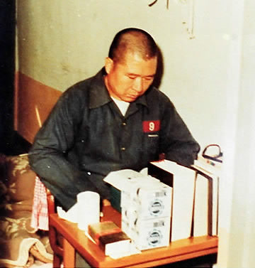 Kim Dae-jung sitting a desk reading in prison. 