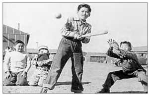 A boy stand in the middle of four boys is playing ball games.