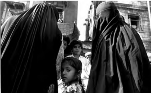 Photo of a little girl turns around in the middle of two people dressed in black