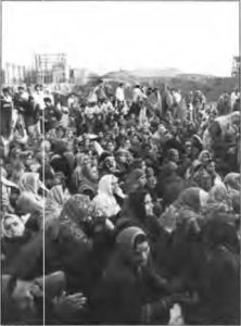 photo of a large group of people, sitting and clasping their hands in prayer