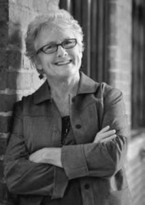 photograph of a woman with her arms crossed, smiling.