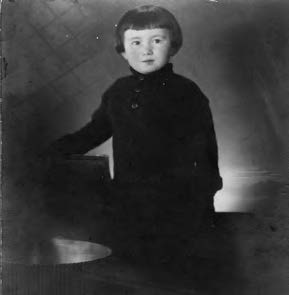 a photograph of a young child in dark clothing, staring forward.