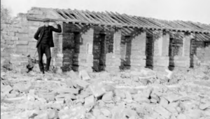 Image shows a male standing next to an unfinished house